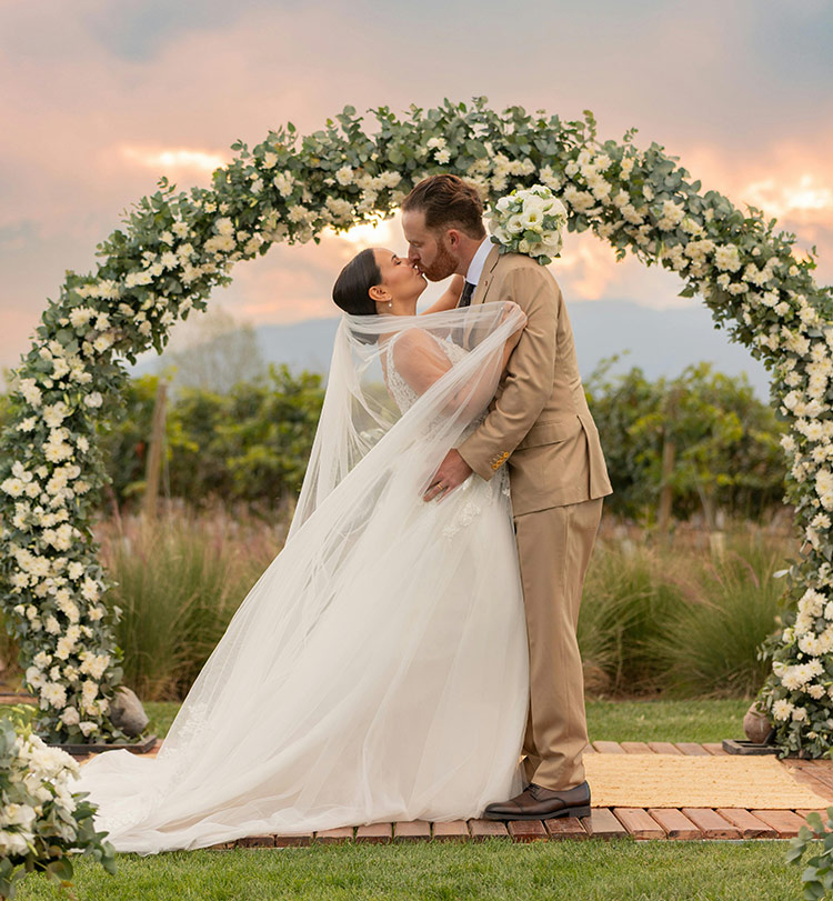 Outdoor wedding ceremony with floral arch at sunset